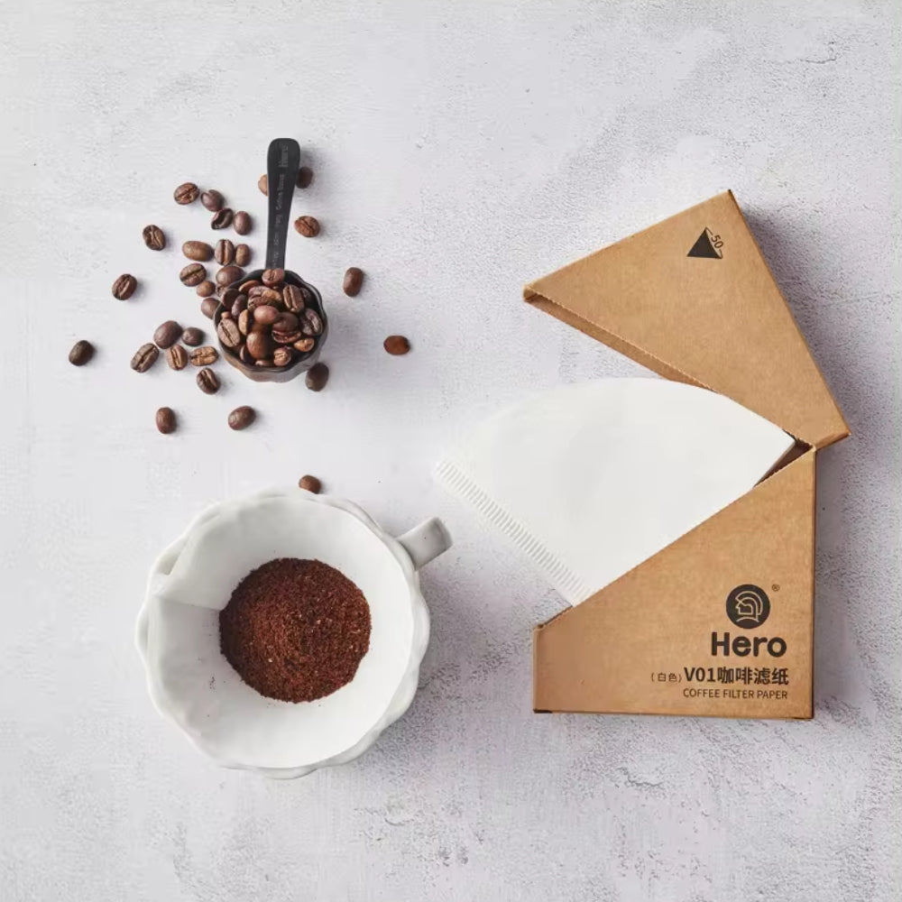 LAMOSE V01 white coffee paper filters in an open brown box, shown overhead with roasted coffee beans and ground coffee in a ceramic dripper.
