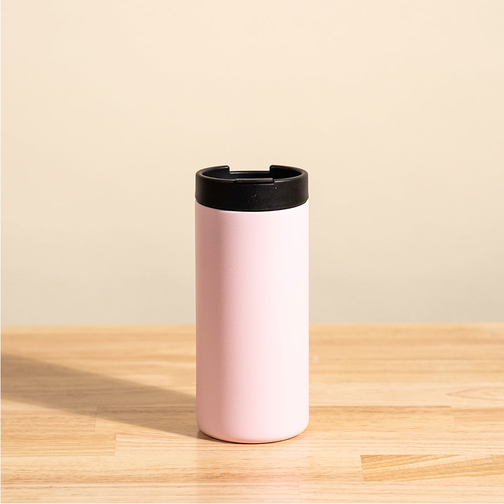 LAMOSE Grouse 12 oz insulated tumbler in baby pink, shown from the back, featuring a matte finish and a black sip lid, standing on a wooden surface.