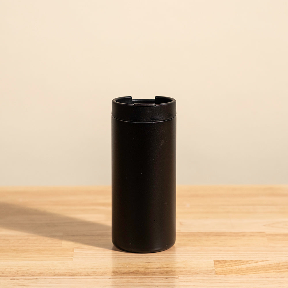 LAMOSE Grouse 12 oz insulated tumbler in onyx black, straight-on view. Matte stainless steel finish with an open top, resting on a wooden table.